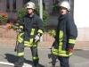 Zwei Feuerwehrmänner. Dazwischen ein Unterflurhydrant.