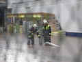 Zwei Feuerwehrangehörige bringen eine Pumpe auf dem Gelände des Baumarkts in Stellung.