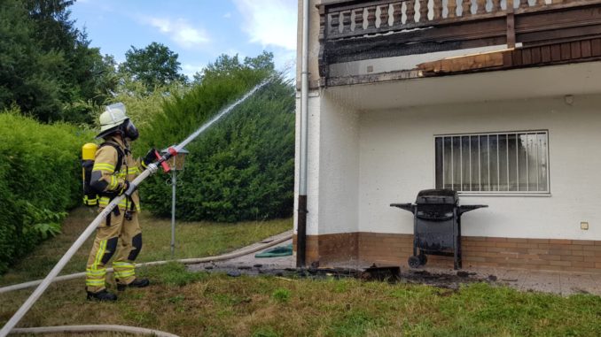 Ein Feuerwehrmann löscht den brennenden Balkon.