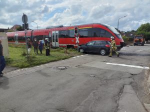 Personenzug und Pkw am Bahnübergang.