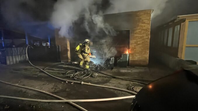 Einsatzkräfte mit Atemschutz öffneten das Garagentor mithilfe einer Rettungssäge.